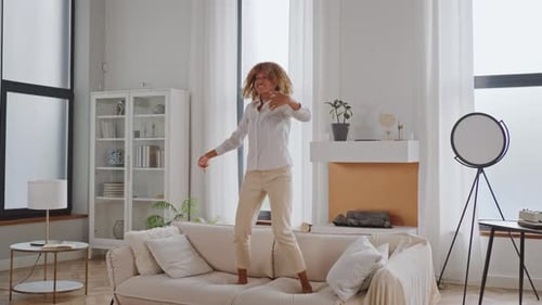 Woman Dances Joyfully on Sofa in Modern Home