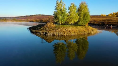 prise de vue en orbite aérienne d'une île avec des bouleaux avec reflet dans l'eau du lac au lever du soleil pendant f