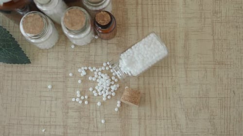 Homeopathic Pills in Glass Jars on Wooden Surface