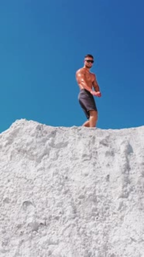 Sporty man posing on mountain. Aerial view of posing man on top of mountain Vertical video