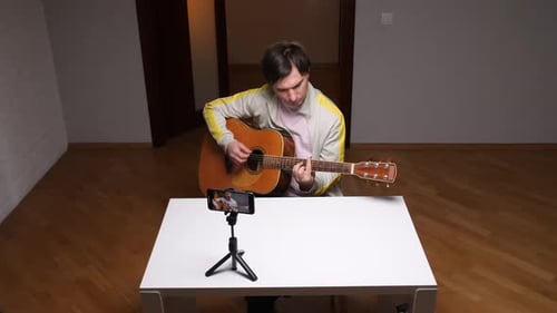 Young Adult Plays Guitar, Records with Phone