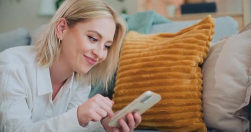 Woman Browsing on Smartphone Relaxing on Sofa