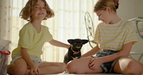 Two Girls Petting a Dog Indoors in Daytime