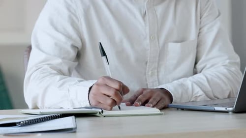 Geschäftsmann händig, arbeitet und schreibt Notizen in einem Tagebuchbuch mit Stift, plant tägliche Aufgaben