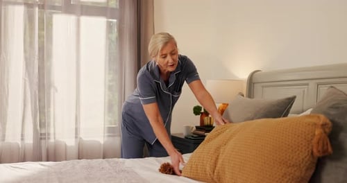 Woman Making Bed with Pillows in Bedroom