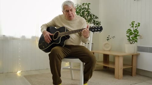 Senior Man Playing Acoustic Guitar at Home
