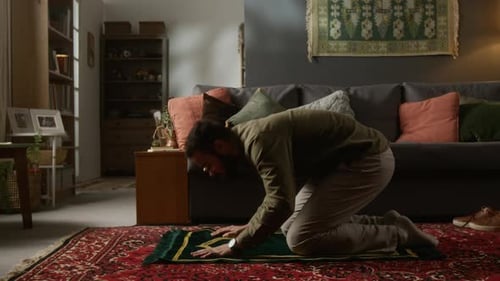 Man Kneeling on Prayer Mat in Living Room