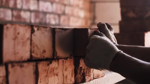 Worker Stacking Red Bricks at Construction Site