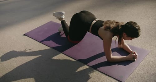 Woman Exercising with Resistance Band Outdoors on Mat