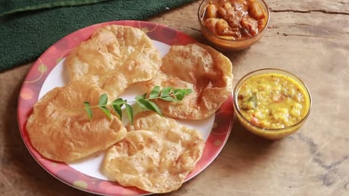 rotation Chole Bhature or Chick pea curry and Fried Puri served in terracotta crockery over wood bac