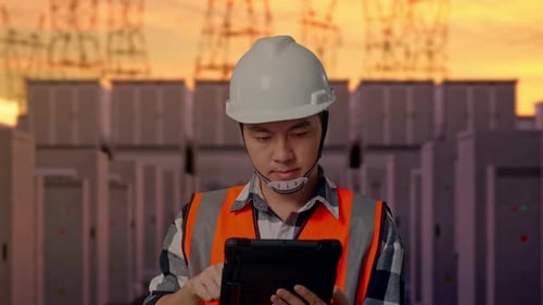 Close Up Of Asian Male Engineer Working On A Tablet with High Voltage Power