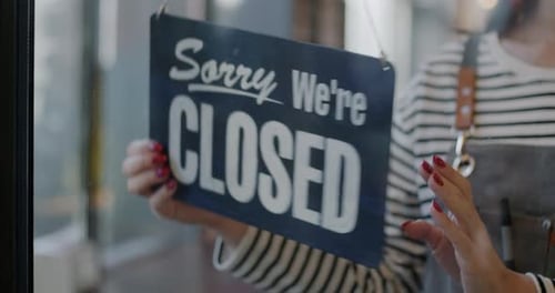 Closeup of Female Hand Waitress Hanging Open Sign on Transparent Cafe Door Inviting Customers