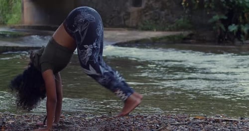 A woman meditating in a yoga position near a river in the Caribbean sunshine.