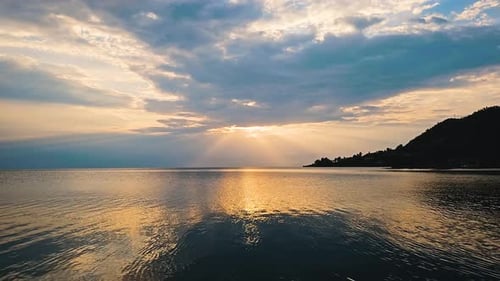 Zeitraffer von Wolken und Sonnenstrahlen über dem See