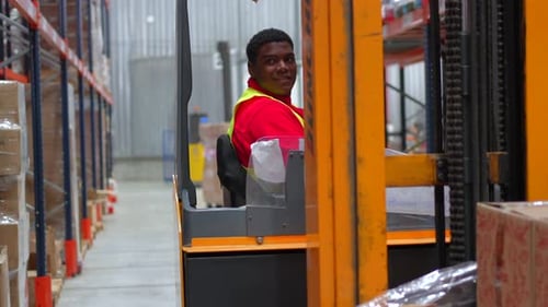Travailleur latin souriant assis sur un chariot élévateur dans un entrepôt de distribution