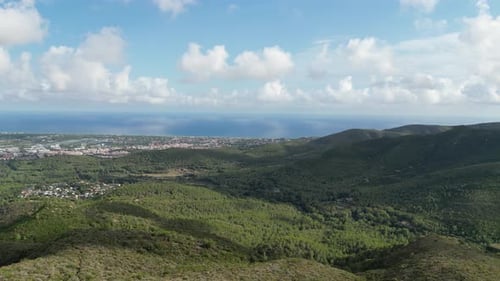 Aerial view of lush mountains and distant city, Spain.