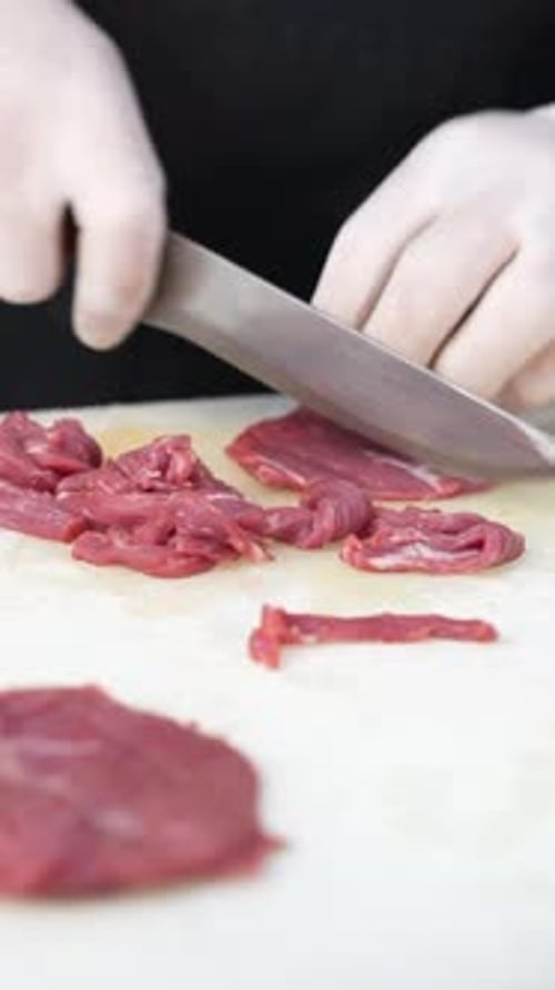 Close-Up of Cook Slicing Raw Beef on Board