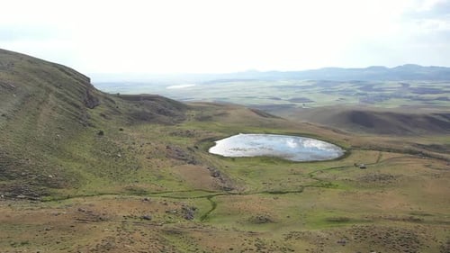 Vue aérienne des collines, des prairies vertes et de l'étang