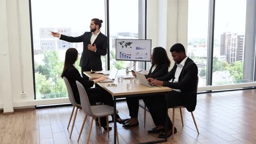 Business Presentation with Graphs to Multiracial Colleagues in Modern Office
