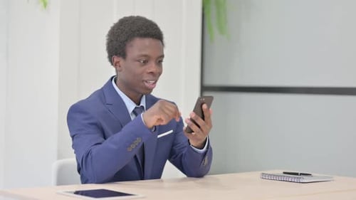 Man Celebrating Success on Smartphone in Office
