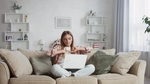 Woman Using Laptop Relaxing On Sofa At Home
