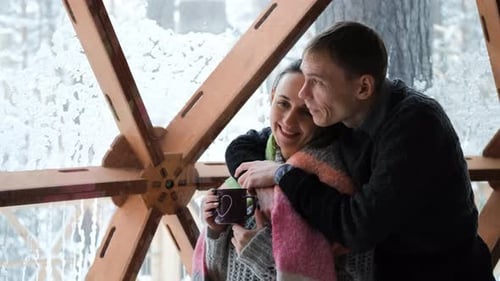 Pareja mirando la naturaleza invernal en un glamping