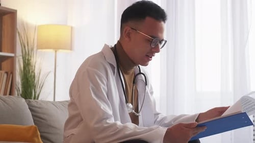 Young Adult Doctor Reviewing Medical Chart Indoors
