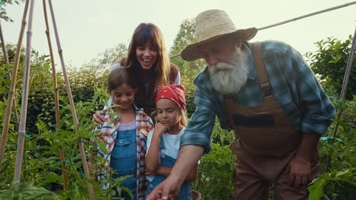 Family Gathers in Garden Learning About Growing Plants