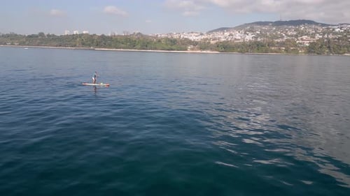Aerial View of a Man Paddling a Standup Paddleboard or SUP Board on a Calm Sea