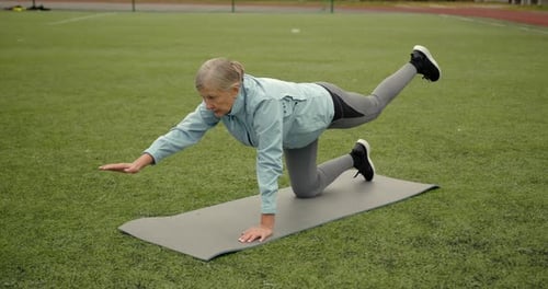 Aged Woman Doing Exercises in Public Stadium