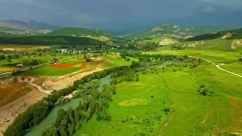 A large, lush green field with a dirt road running through it