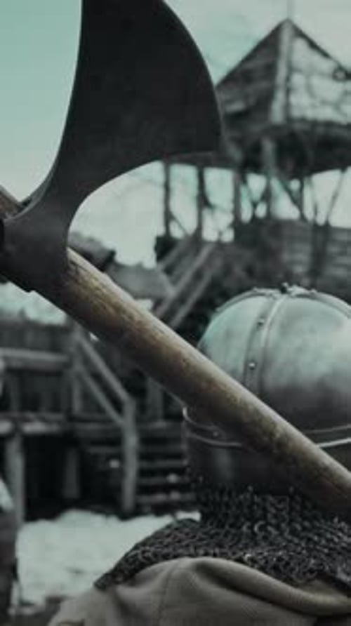 Warrior in Chainmail and Helmet Standing in Fort Yard with Axe on Shoulder