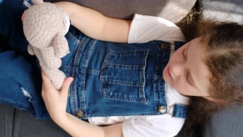 Top view of child hugging teddy bear and smiling, little girl playing with favorite toy