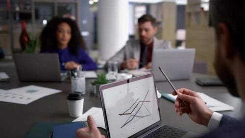 Gemischtrassige Geschäftsleute diskutieren im Konferenzbriefing mithilfe von Laptop Graph über Forschungstabellen. Taucher