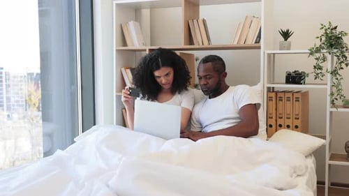 Couple Shopping Online in Bed with Laptop and Card