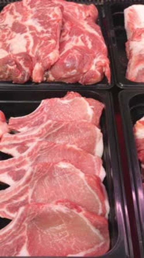 Variety of packaged raw meat cuts in trays