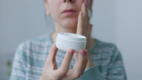 Woman Applies Lotion to Face for Skincare Routine