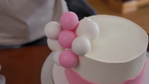 High Angle View Decorating Cake with Pink and White Edible Sugar Balls Indoors