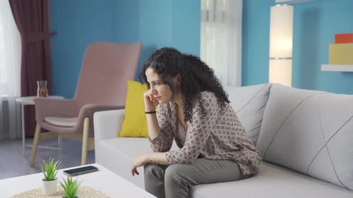 Pensive Woman Sitting on Sofa at Home
