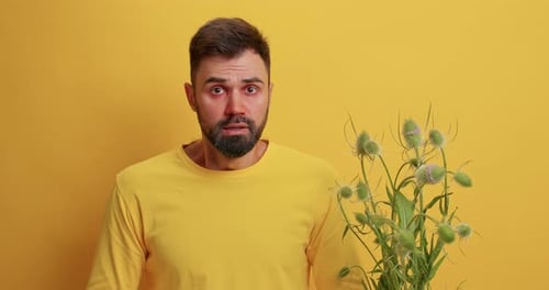 Man With Allergies Sneezing Next to Flowering Plant