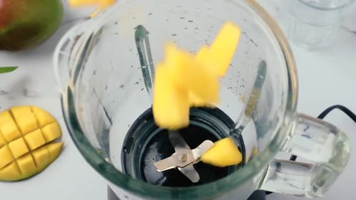 Preparing a Bright Yellow Mango Smoothie in Blender