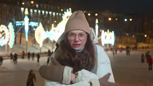 Woman Shivers on a Lit Ice Rink at Night