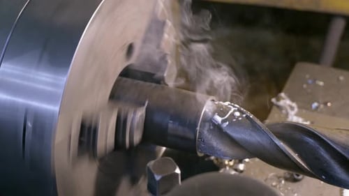 Drilling detail on lathe with metal shavings.