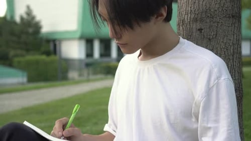 Attractive Asian Man with Textbook Studying Outdoors in the Park