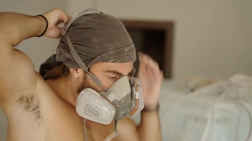Man Puts on Respirator Mask Indoors for Protection