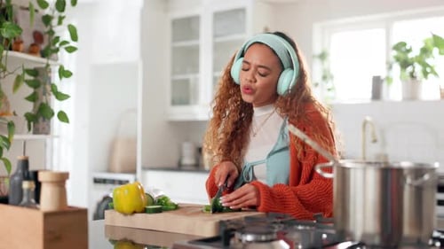 Young Woman Cooking Vegetables in Kitchen with Headphones