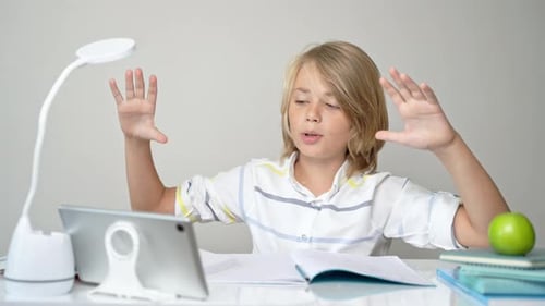 Middle School Smiling Student Boy Sitting at Desk Remote Studying Writing Book Homework and Tablet