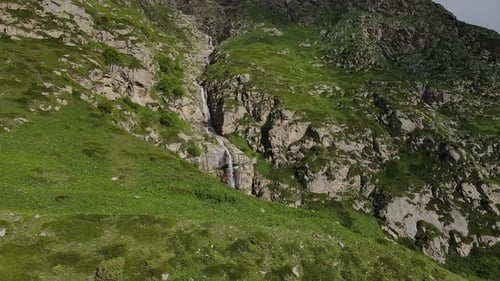Aerial View of a Waterfall Flowing Down the Slope of a Gorge in the Mountains