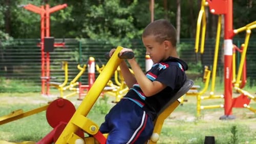 Child Boy Engaged on Sports Training Simulator at the Street in Slow Motion