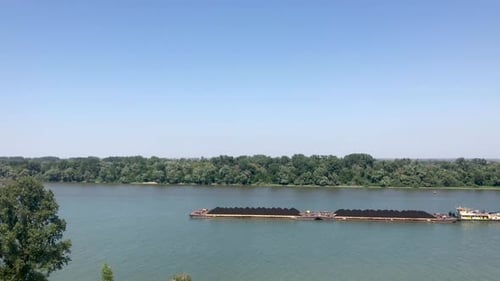 Aerial view of coal freight carrier transporting through Danube river in 4k on sunny day in Belgrade